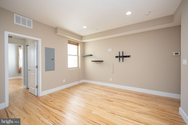 empty room with light hardwood / wood-style floors and electric panel