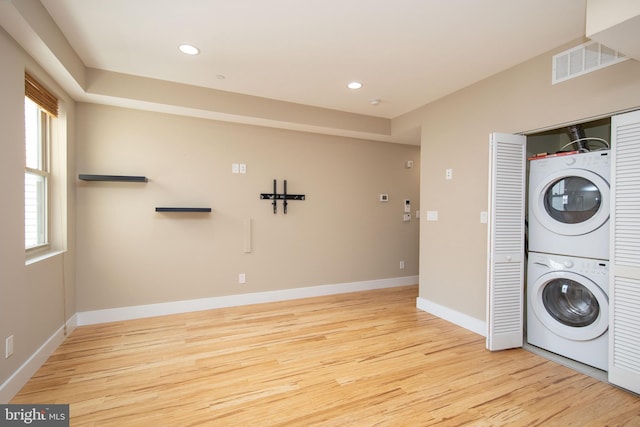 laundry area featuring stacked washer / drying machine and light hardwood / wood-style floors