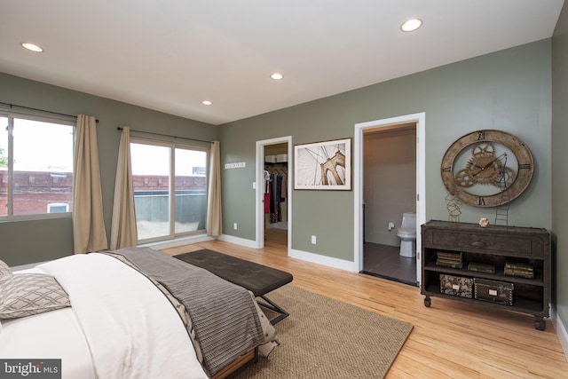 bedroom with a closet, a walk in closet, connected bathroom, and light hardwood / wood-style flooring