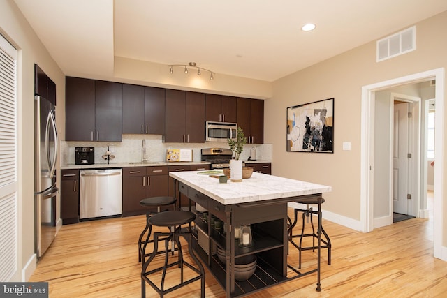 kitchen with dark brown cabinets, stainless steel appliances, tasteful backsplash, and sink