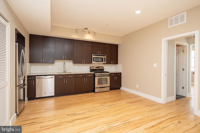 kitchen featuring sink, stainless steel appliances, tasteful backsplash, light hardwood / wood-style floors, and dark brown cabinets