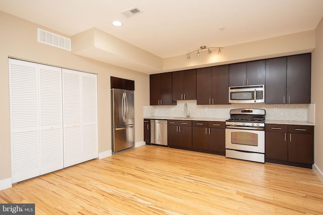 kitchen with sink, stainless steel appliances, tasteful backsplash, light hardwood / wood-style flooring, and dark brown cabinets