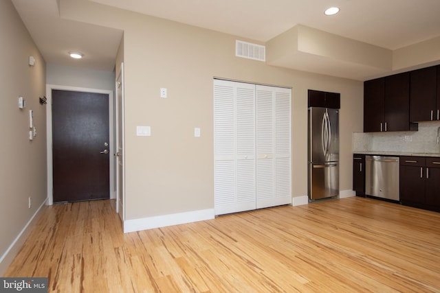 kitchen with decorative backsplash, light hardwood / wood-style floors, dark brown cabinetry, and appliances with stainless steel finishes