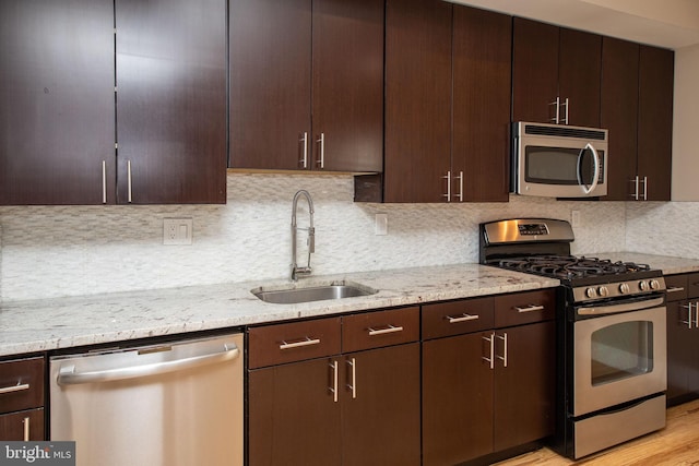 kitchen featuring light stone countertops, decorative backsplash, sink, and stainless steel appliances