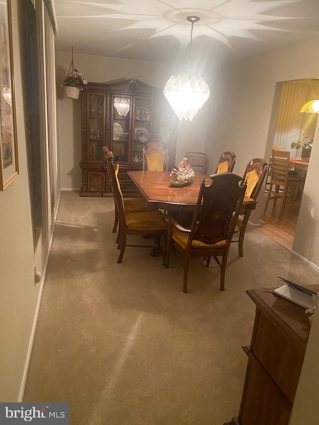 dining space featuring carpet and an inviting chandelier