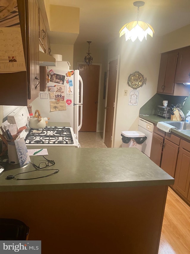 kitchen featuring decorative light fixtures, sink, light hardwood / wood-style floors, and white appliances