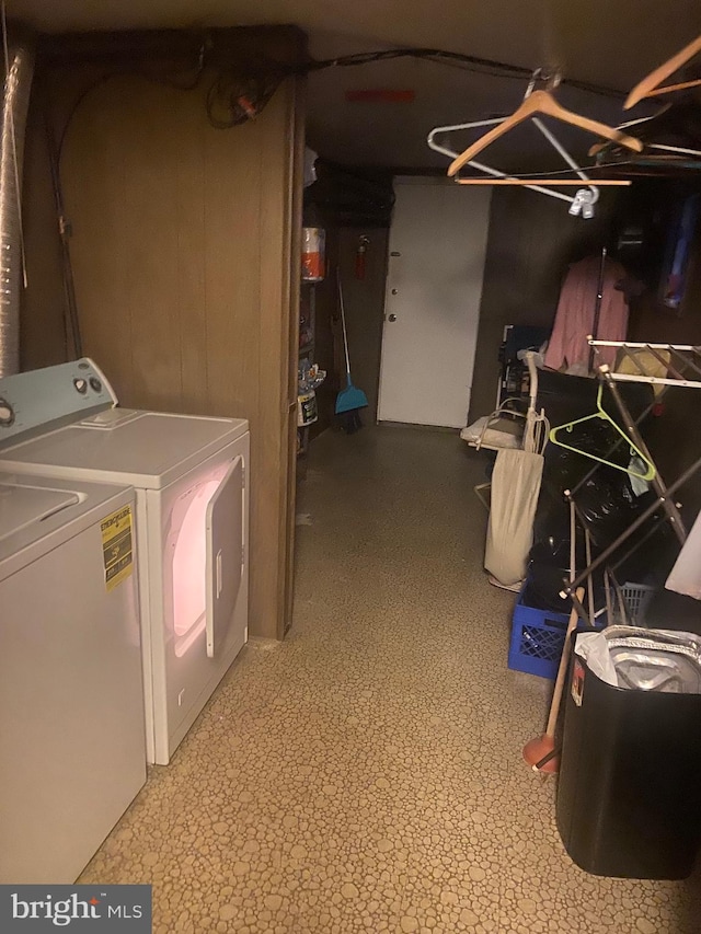 laundry area featuring wood walls and separate washer and dryer