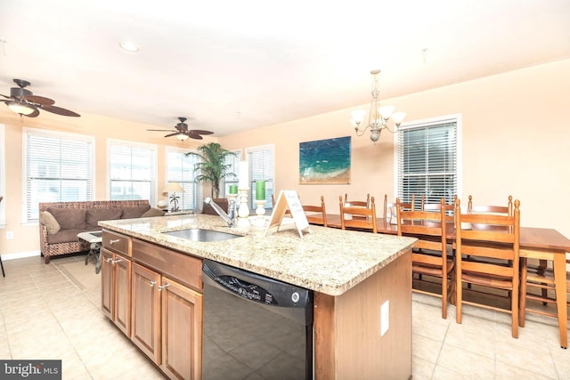 kitchen with pendant lighting, sink, light stone counters, black dishwasher, and an island with sink