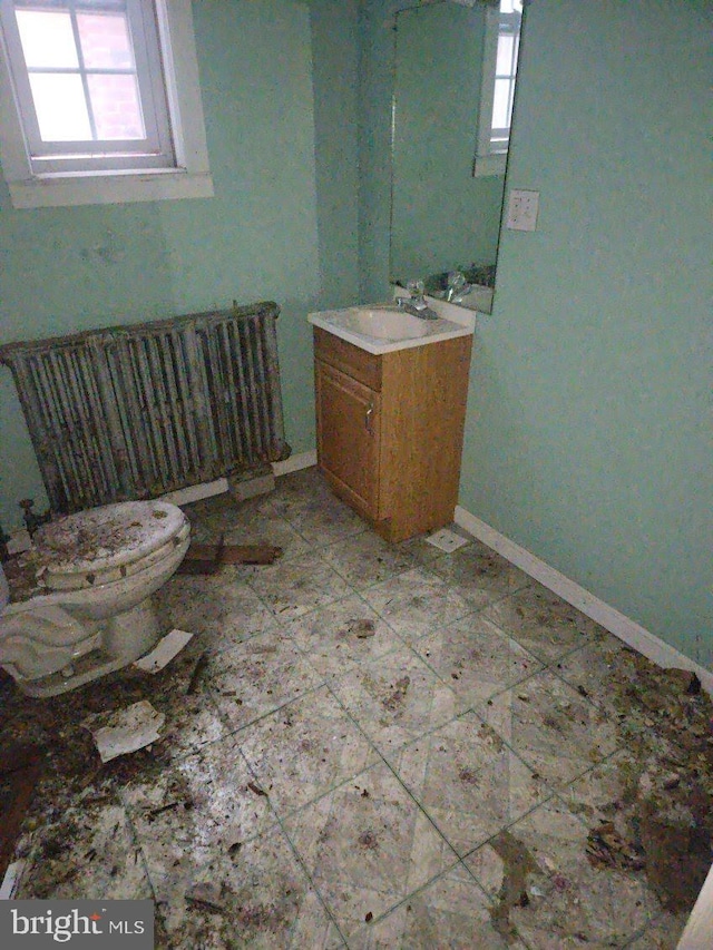 bathroom featuring vanity, a healthy amount of sunlight, toilet, and radiator heating unit