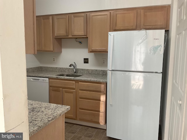 kitchen featuring light stone countertops, sink, and white appliances