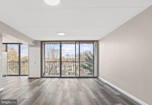 empty room with a wall of windows and hardwood / wood-style flooring