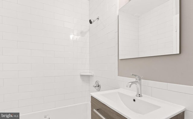 bathroom with tiled shower / bath combo and vanity