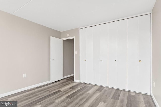 unfurnished bedroom with light wood-type flooring and a closet