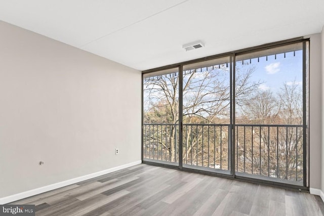 empty room with a wall of windows and hardwood / wood-style floors