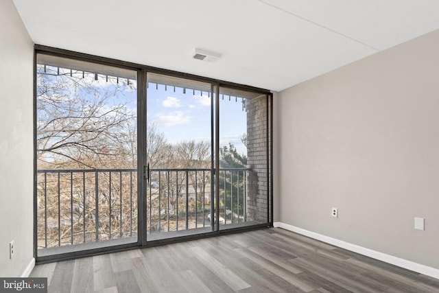 unfurnished room featuring expansive windows and hardwood / wood-style flooring