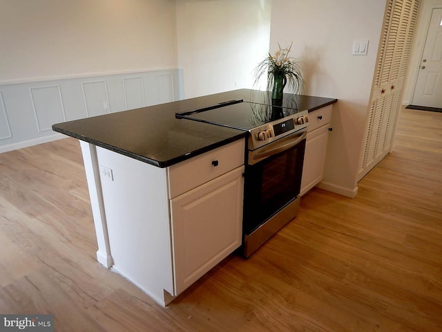 kitchen with electric range, white cabinets, and light hardwood / wood-style flooring