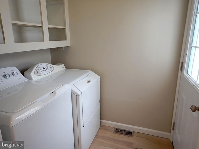 laundry area with washing machine and dryer and light wood-type flooring