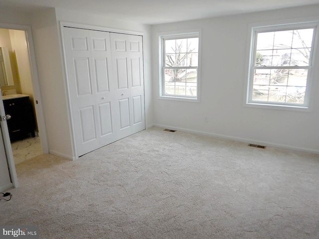 unfurnished bedroom with a closet, light colored carpet, and multiple windows