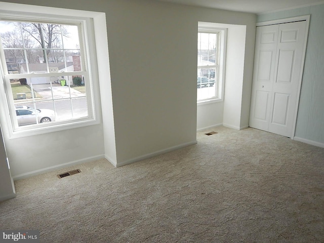 unfurnished bedroom featuring multiple windows, a closet, and light colored carpet