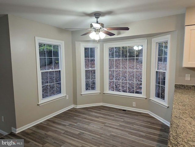 unfurnished dining area featuring ceiling fan and dark hardwood / wood-style flooring