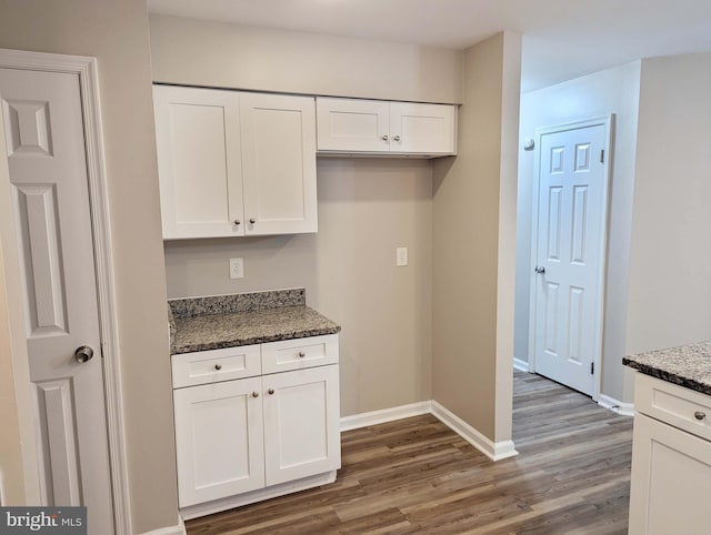 kitchen with white cabinets, dark hardwood / wood-style floors, and dark stone countertops