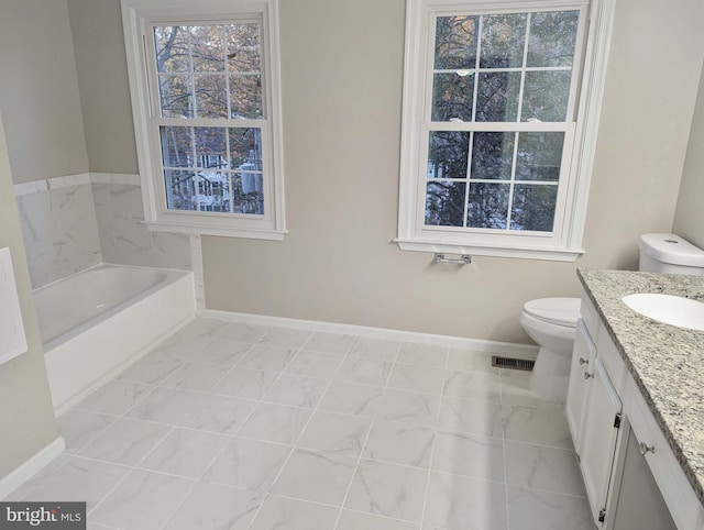 bathroom with vanity, a tub to relax in, toilet, and a healthy amount of sunlight