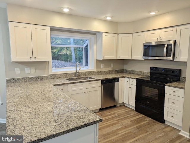 kitchen with light stone countertops, sink, light hardwood / wood-style flooring, white cabinets, and appliances with stainless steel finishes