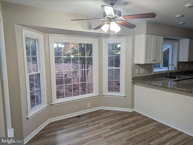 kitchen featuring sink, ceiling fan, dark stone countertops, white cabinetry, and wood-type flooring