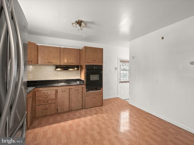 kitchen with backsplash, oven, and stainless steel refrigerator