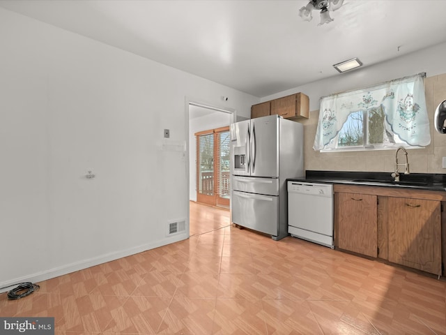 kitchen featuring sink, white dishwasher, and stainless steel fridge