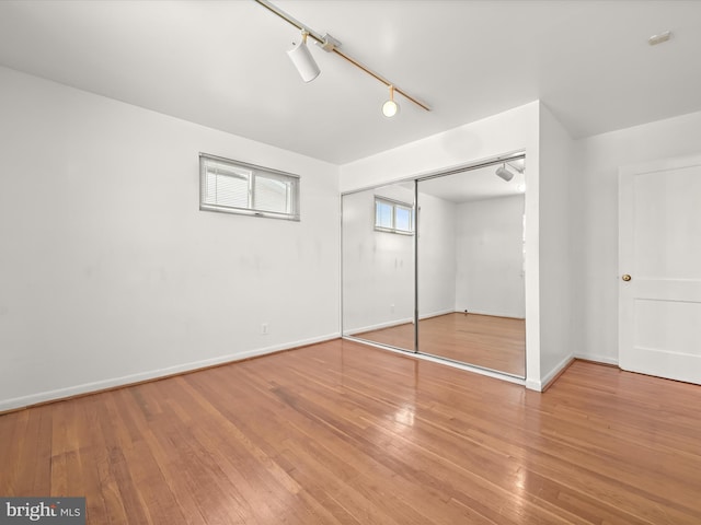 unfurnished bedroom with hardwood / wood-style floors, a closet, and track lighting