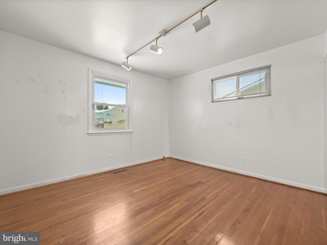 empty room with hardwood / wood-style floors and track lighting