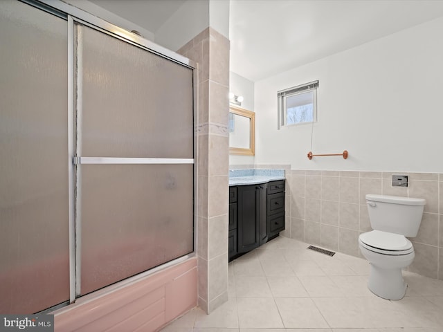 bathroom featuring tile patterned floors, a shower with door, vanity, tile walls, and toilet