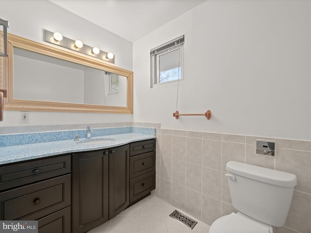 bathroom with tile walls, toilet, vanity, and tile patterned flooring