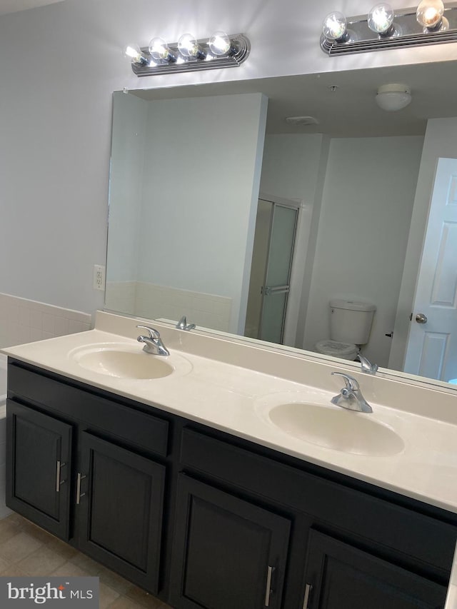 bathroom with tile patterned flooring, vanity, a shower with shower door, and toilet