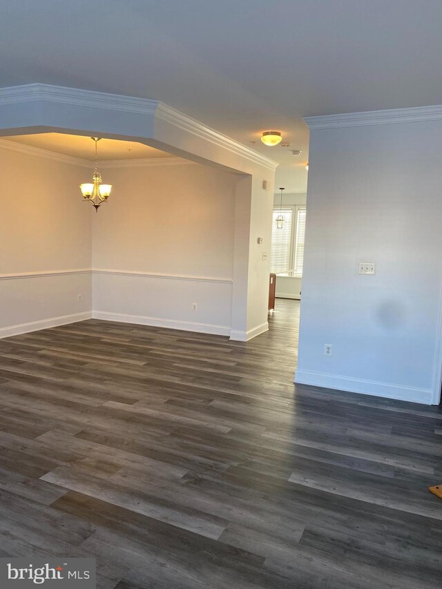 unfurnished room with crown molding, a chandelier, and dark hardwood / wood-style floors