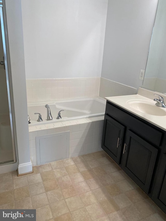 bathroom featuring vanity and a relaxing tiled tub