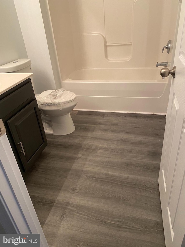 full bathroom featuring wood-type flooring, vanity, shower / bath combination, and toilet