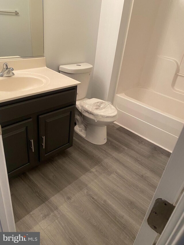 full bathroom with vanity, toilet, wood-type flooring, and tub / shower combination