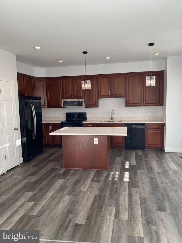 kitchen with dark wood-type flooring, pendant lighting, black appliances, and sink