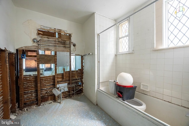 bathroom with tile patterned floors and a tub to relax in