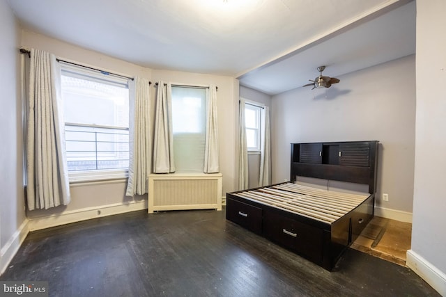 bedroom with radiator heating unit, dark hardwood / wood-style floors, vaulted ceiling, and multiple windows