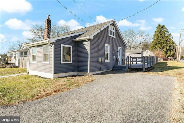 view of side of home with a deck and a lawn