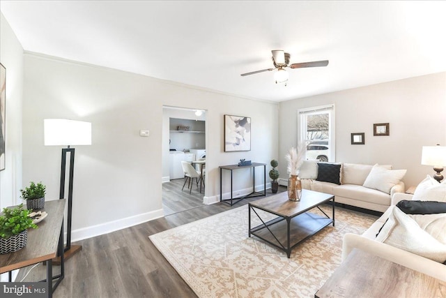 living room featuring ceiling fan, washer / dryer, and dark wood-type flooring