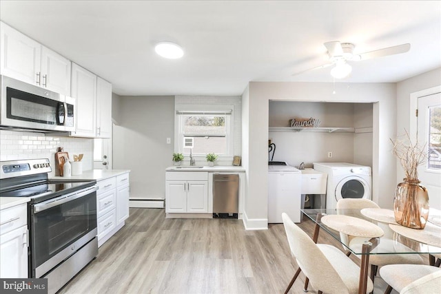 kitchen with white cabinetry, washer and clothes dryer, sink, and appliances with stainless steel finishes