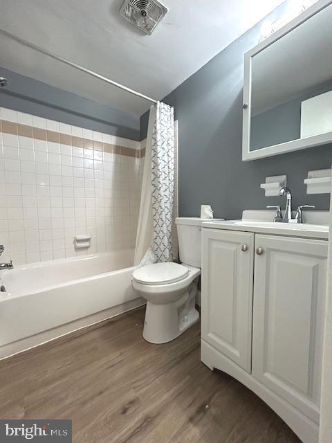 full bathroom with shower / bath combination with curtain, vanity, hardwood / wood-style flooring, and toilet