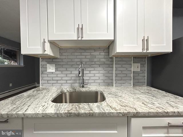 kitchen with white cabinets, backsplash, and sink