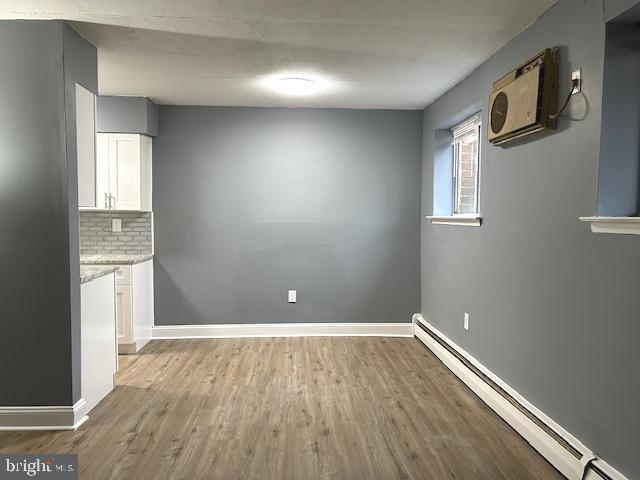 unfurnished dining area with hardwood / wood-style flooring and baseboard heating