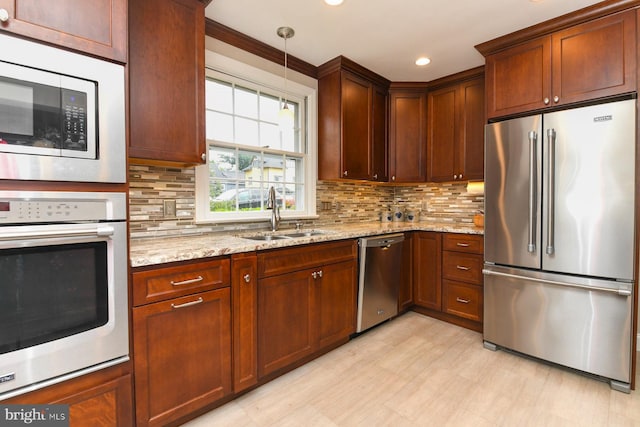 kitchen with pendant lighting, sink, light stone countertops, tasteful backsplash, and stainless steel appliances