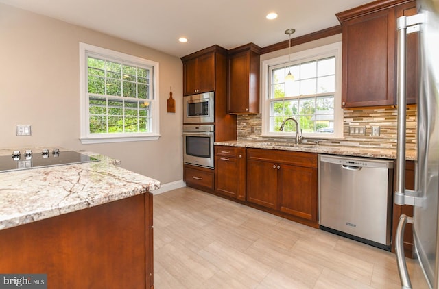 kitchen with backsplash, sink, hanging light fixtures, and appliances with stainless steel finishes